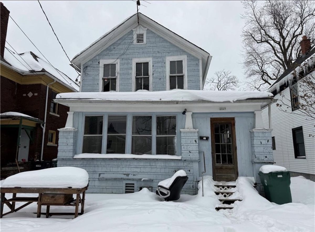 Blue clapboard house under snow in Buffalo, New York, kept heated and secured through the winter